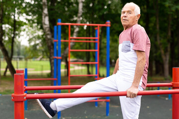 Fototapeta premium Senior man performing parallel bar exercises in park