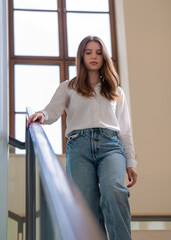 A young student walks along a glass staircase. Portrait of a cute girl on the steps