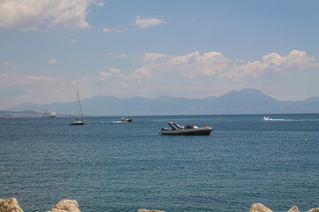 Obraz premium Sailing boat on the blue sea on the background of mountains and Mount Visuvius in the Bay of Naples, southern Italy. Yachts on the coast