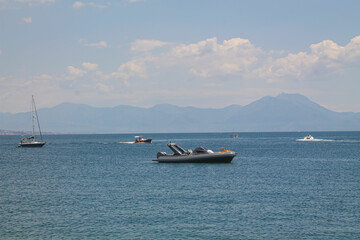 Obraz premium Sailing boat on the blue sea on the background of mountains and Mount Visuvius in the Bay of Naples, southern Italy. Yachts on the coast