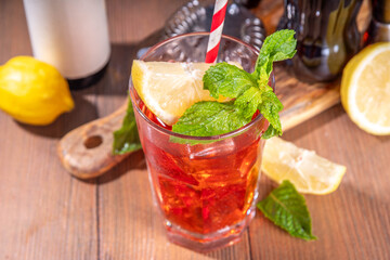 Cola and wine sweet sour alcoholic drink, Kalimotxo or calimocho boozy fizzy cocktail with ice cubes, lemon and mint, copy space