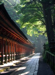 Obraz premium Long traditional wooden temple corridor with red columns and stone path in a lush green forest
