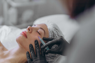 A professional beautician injects into the face of a young woman