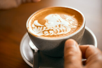a cup of hot latte art coffee on wooden table