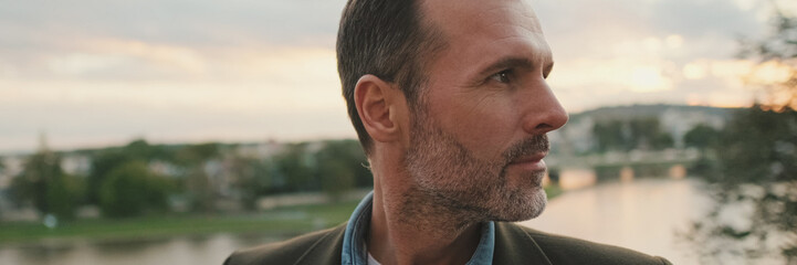 Obraz premium Man looks around standing against the background of the river, panorama