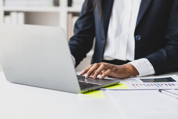 Businesswoman typing and pointing at laptop screen while working on laptop in office.