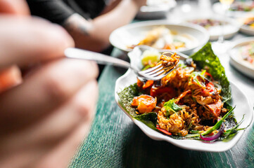 Close-up of a vibrant, healthy salad with mixed vegetables and grains, being eaten with a fork, suggesting a focus on nutritious dining