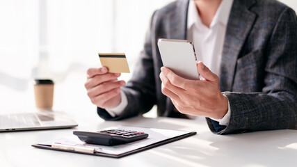 A man is sitting at a desk with a laptop and a calculator