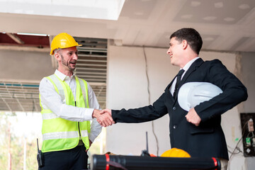 Two men shaking hands, one wearing a yellow vest