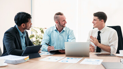 Three men are sitting at a table in a business meeting