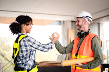 A construction worker shakes hands with a woman in a yellow vest