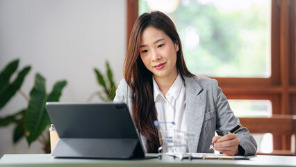 A woman is sitting at a desk with a laptop and a notebook