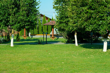 Green grass lawn with trees and gazebo