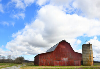 Red Wooden Barn With Silo and Dirt Lane