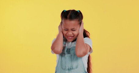 Girl, child and cover ears in studio with frustrated face for noise, anxiety and fear by yellow background. Kid, hands and block for hearing, sound and loud with stress, clothes and audio sensitivity