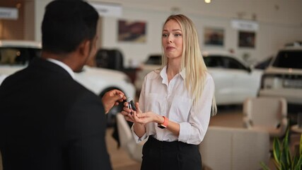 Portrait of happy blonde customer female thanking African-American dealer male wearing suit for helping to choose car to buy in dealership center. Concept of choosing and buying new car at showroom.