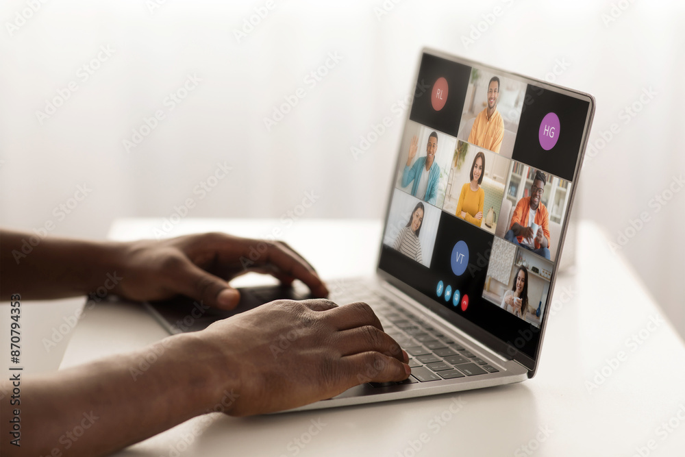 Poster a person is sitting at a desk, using a laptop to participate in a video conference with several othe