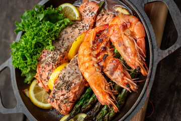 Healthy baked salmon steaks with greens and asparagus in a black cast iron skillet. A delicious low-carb breakfast.