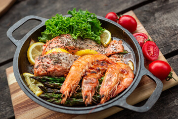 Healthy baked salmon steaks with greens and asparagus in a black cast iron skillet. A delicious low-carb breakfast.