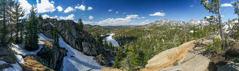 A panoramic view of a mountain range with snow-covered trees and a river