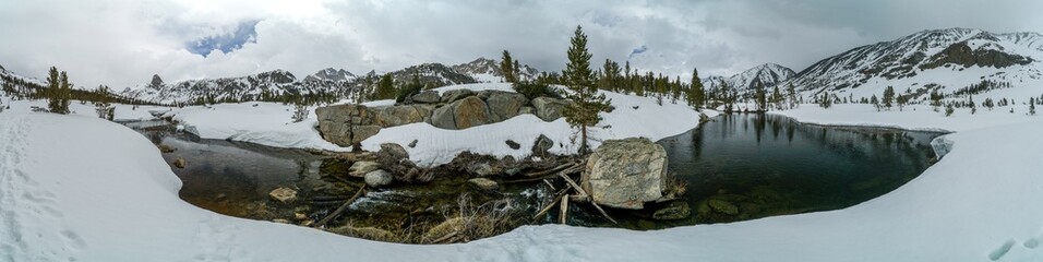A panoramic view of a snowy landscape with a river running through it