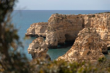 Scenic view of a sandy beach with rocky cliffs and clear blue water in Algarve, Portugal