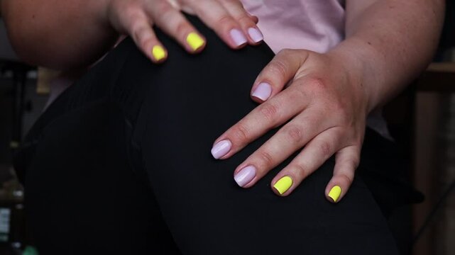 Close-up of a worried girl before an interview or exam, struggling with anxiety. She sits on a chair, tapping her fingers and rubbing her knee while waiting, battling a bad mental health day.
