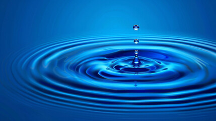 A single clean water droplet falls into the water, creating ripples in a clear blue setting