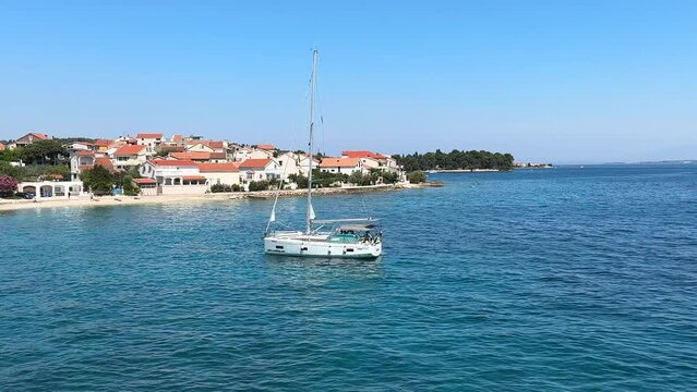 A white sailboat sails on the blue sea. Boat with a sail on the birch water of the Adriatic sea. Sailing holidays off the Croatian coast, Preko island, June 27, 2024