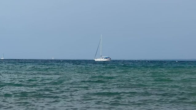 A white sailboat sails on the blue sea. Boat with a sail on the birch water of the Adriatic sea. Sailing holidays off the Croatian coast, Preko island, June 27, 2024