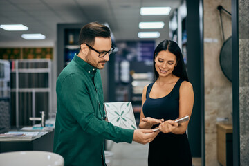 Obraz premium A female customer searching for ceramic tiles, getting recommendations from a male seller.