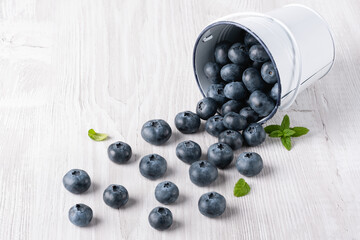 Blueberries poured from a small bucket on a white background