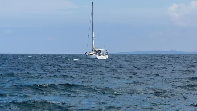 A white sailboat sails on the blue sea. Boat with a sail on the birch water of the Adriatic sea. Sailing holidays off the Croatian coast, Preko island, June 27, 2024