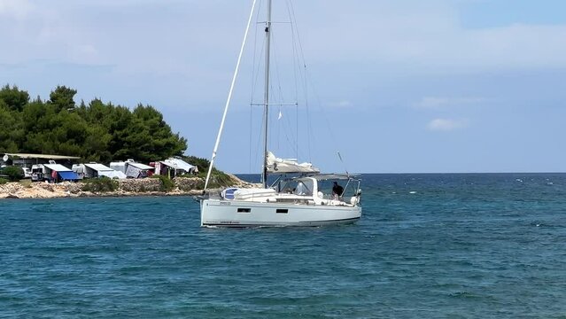 A white sailboat sails on the blue sea. Boat with a sail on the birch water of the Adriatic sea. Sailing holidays off the Croatian coast, Preko island, June 27, 2024