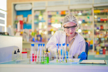 female scientist Experimenting through tubes of chemical liquids and plant samples. In a laboratory with test samples in the background in a modern laboratory By testing safely and cleanly.