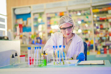 female scientist Experimenting through tubes of chemical liquids and plant samples. In a laboratory with test samples in the background in a modern laboratory By testing safely and cleanly.