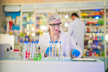 female scientist Experimenting through tubes of chemical liquids and plant samples. In a laboratory with test samples in the background in a modern laboratory By testing safely and cleanly.