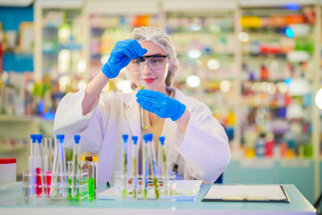 female scientist Experimenting through tubes of chemical liquids and plant samples. In a laboratory with test samples in the background in a modern laboratory By testing safely and cleanly.