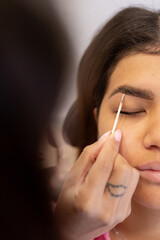 Beautician making eyebrow design and shading procedures. Young latin woman in a professional beauty salon for threading and brow shape correction