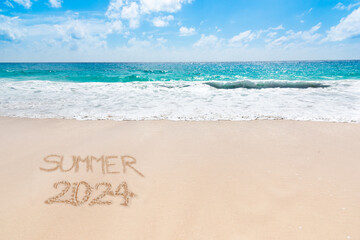 Summer 2024 written on a tropical beach with golden sand