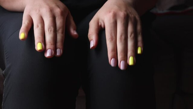 Close-up of a worried girl before an interview or exam, struggling with anxiety. She sits on a chair, tapping her fingers and rubbing her knee while waiting, battling a bad mental health day.