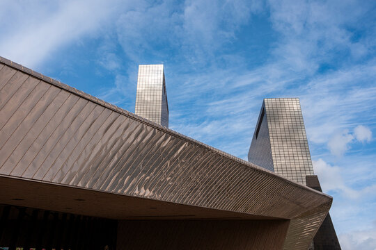An exquisite architectural photograph featuring contemporary silver-toned buildings against a backdrop of a cloudy blue sky, highlighting modern design and elegant structures in Rotterdam