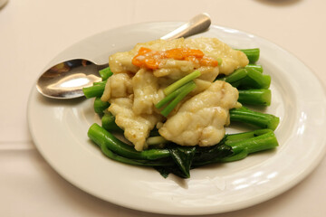 close up of Chinese Hong Kong style Cantonese dish- stir fried choy sum and live rock cod fish