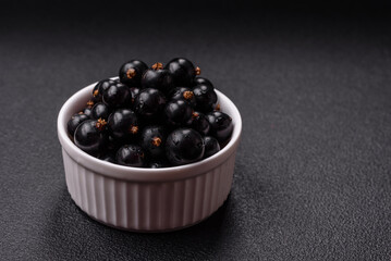 Ripe blackcurrant berries in droplets of water in a ceramic bowl