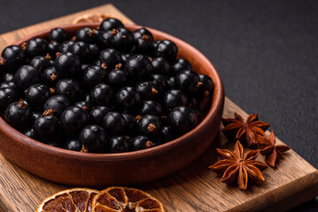 Ripe blackcurrant berries in droplets of water in a ceramic bowl