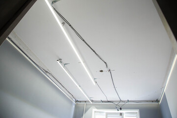 Installation of a suspended modern ceiling with LED light lines in an apartment, industry