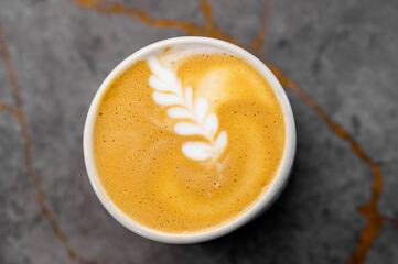 Top view of a freshly brewed cappuccino with latte art on a marbled surface