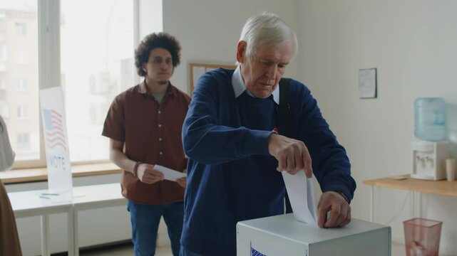 Tilt up shot of diverse American citizens walking one by one to ballot box and putting their voting slips inside it during election day at polling place