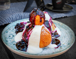 traditional romanian sweet dessert "Papanasi" with deep-fried curd dumplings, sour cream and blueberry pulp