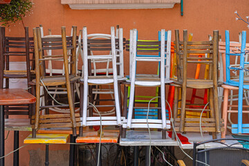Stacks of Up Side Down Colourful Wooden Chairs and Tables in Front of Coffee Shop